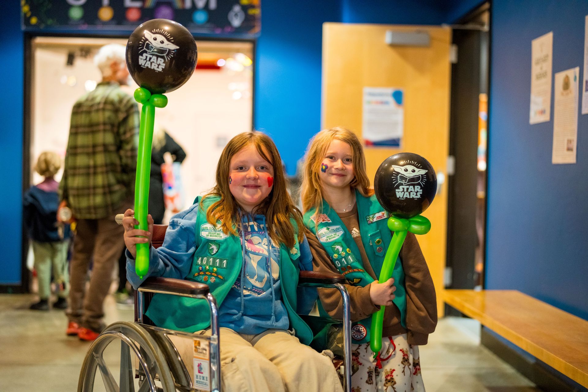 A photo of two girls at the May the Fourth Star Wars celebration at ScienceWorks. One is in a wheel chair.