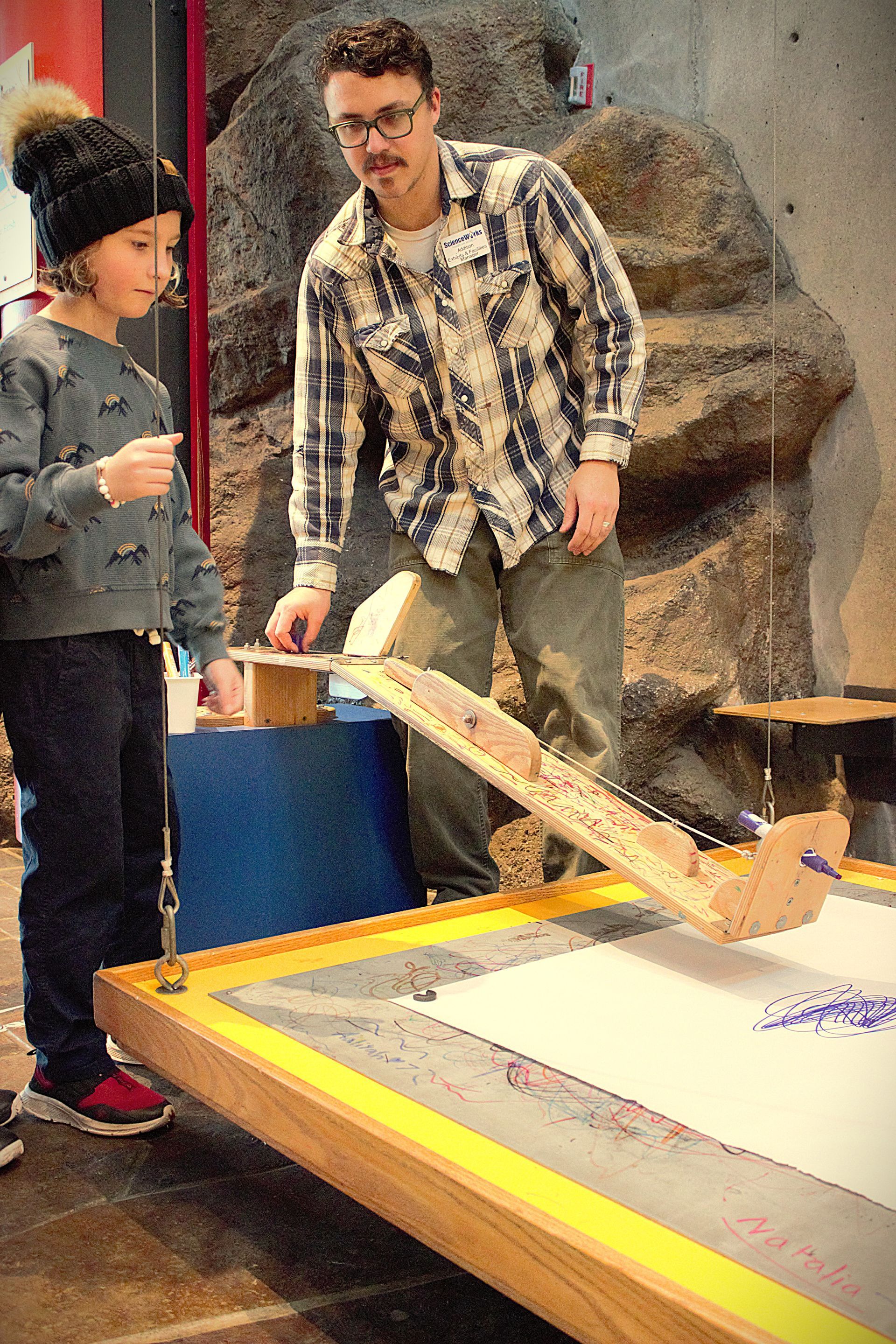 Staff member helping a guest with the Painting Pendulum exhibit at ScienceWorks