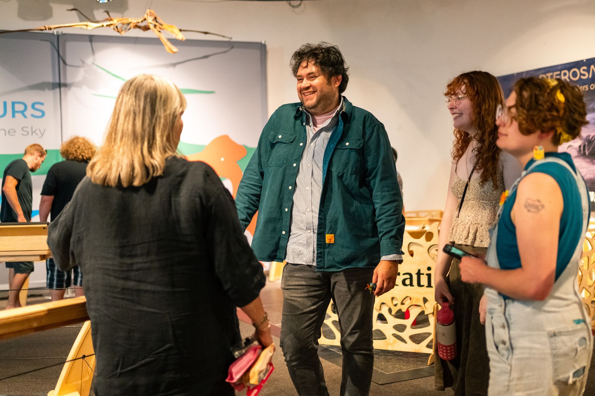 A group of adults chatting and smiling in the Pterosaurs gallery at ScienceWorks