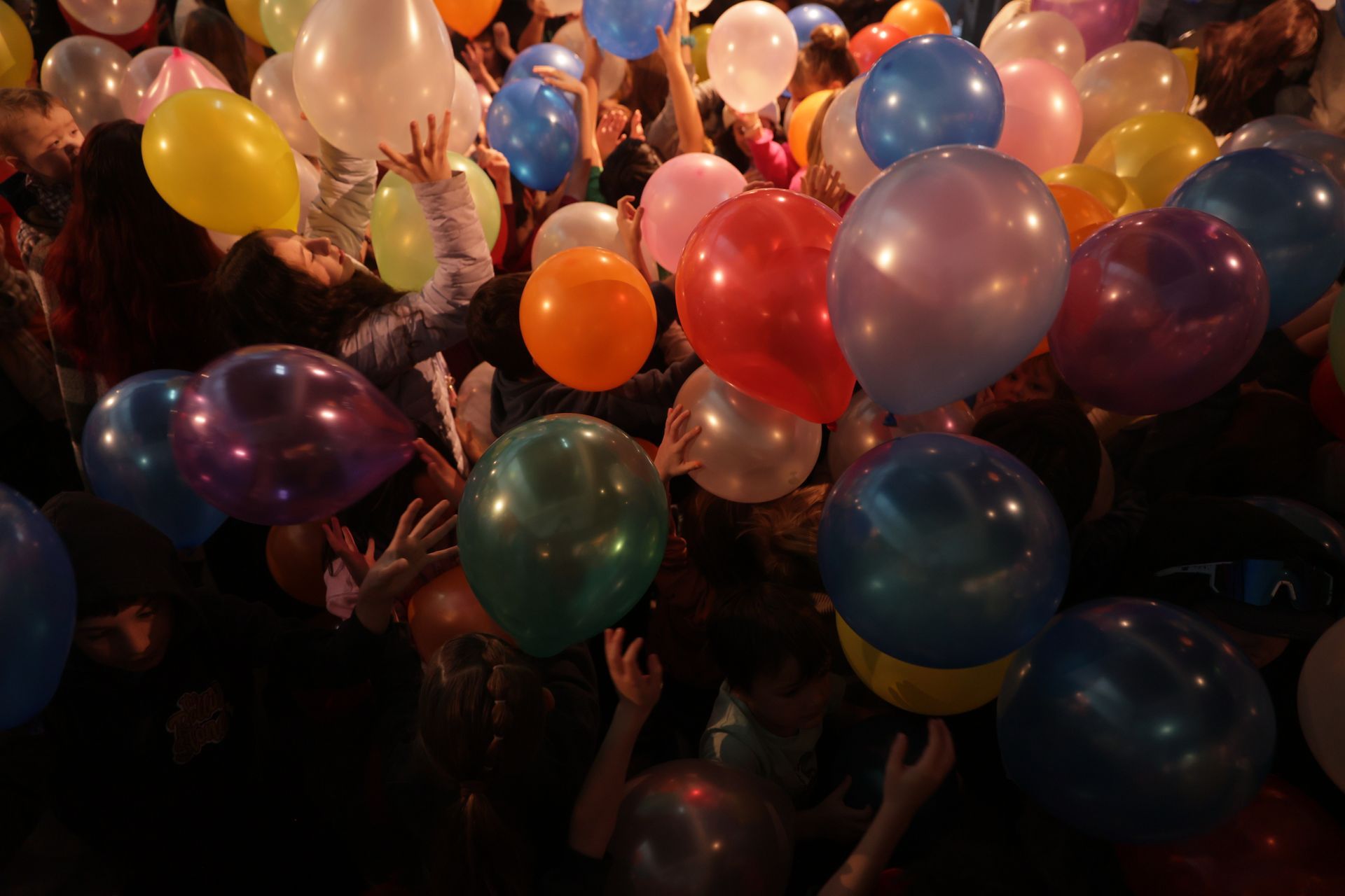 Colorful balloons floating in a crowded area, with people reaching up to touch them at ScienceWorks.