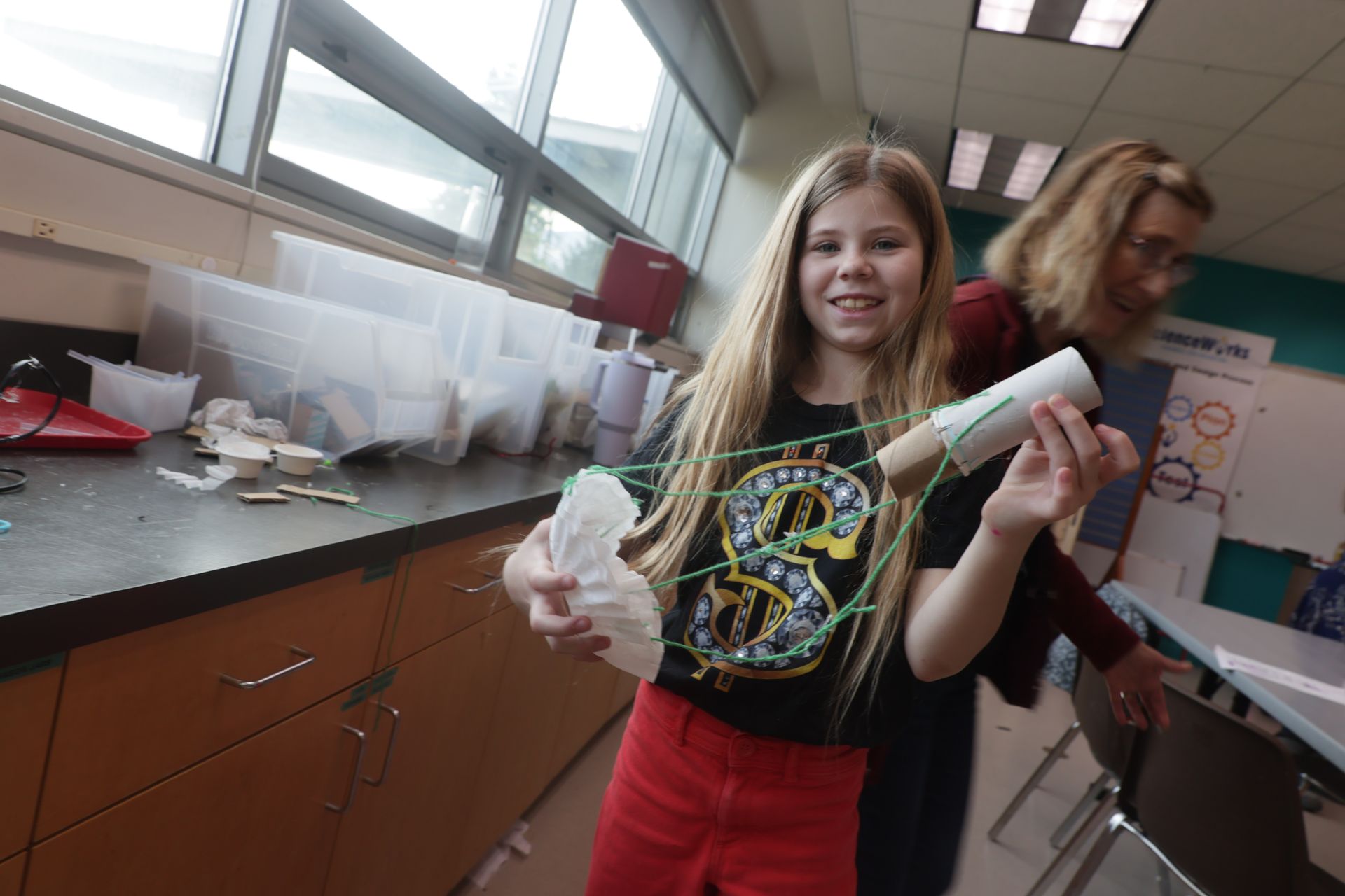 Girl holding a craft made from paper and string for the egg drop challenge at ScienceWorks