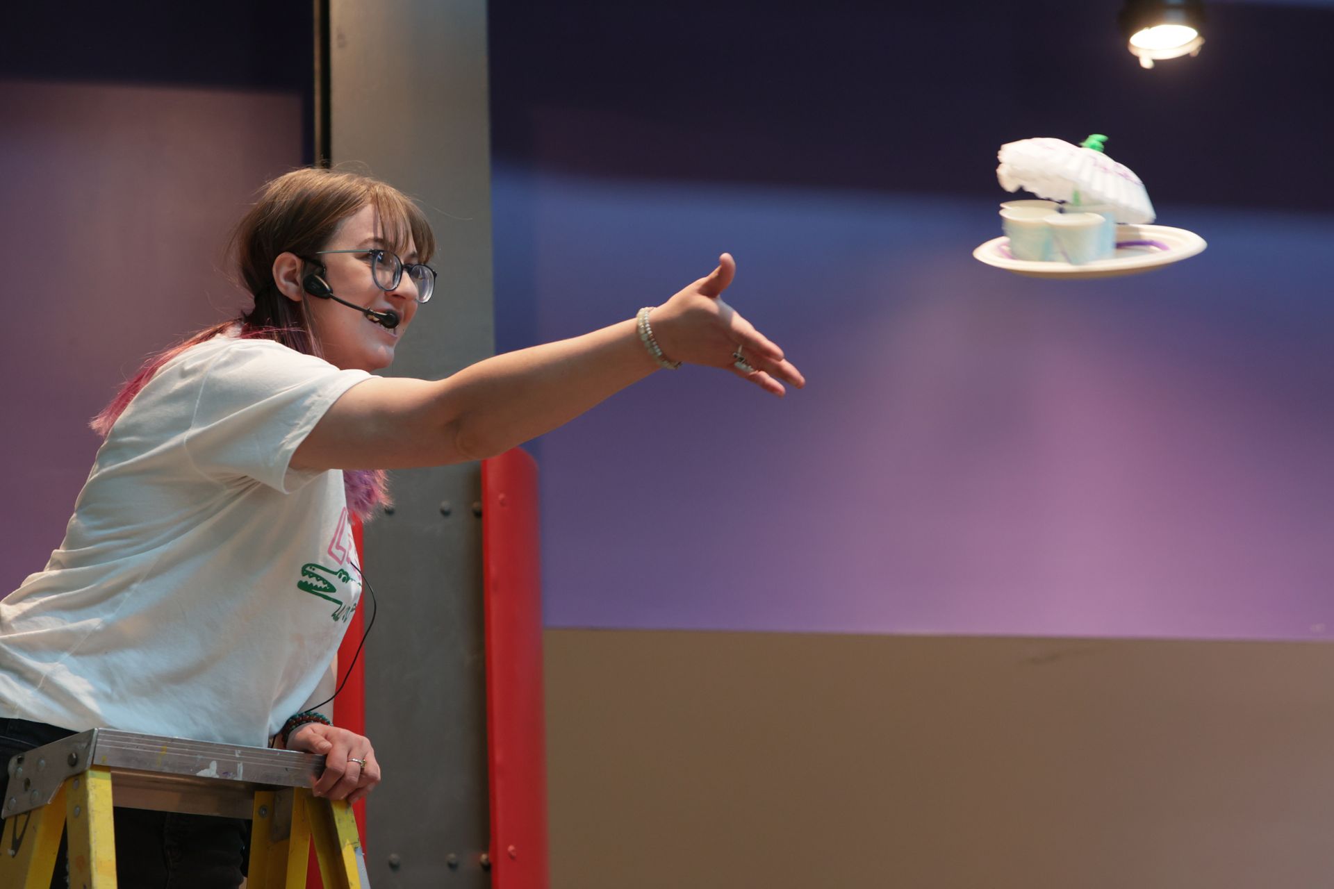 Woman on a ladder, releases an egg drop contraption at ScienceWorks
