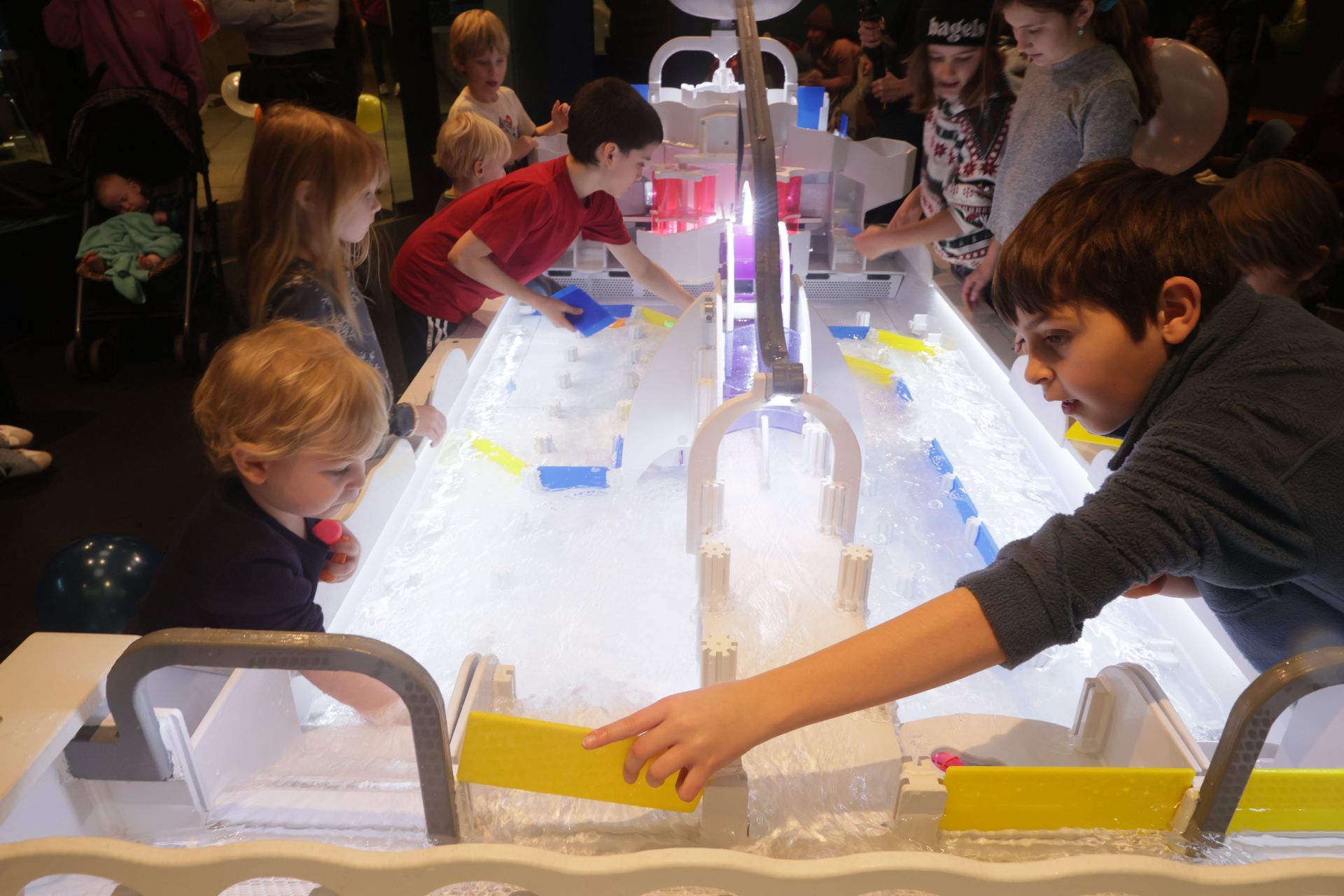 Children playing with water and blocks at an illuminated exhibit at ScienceWorks.