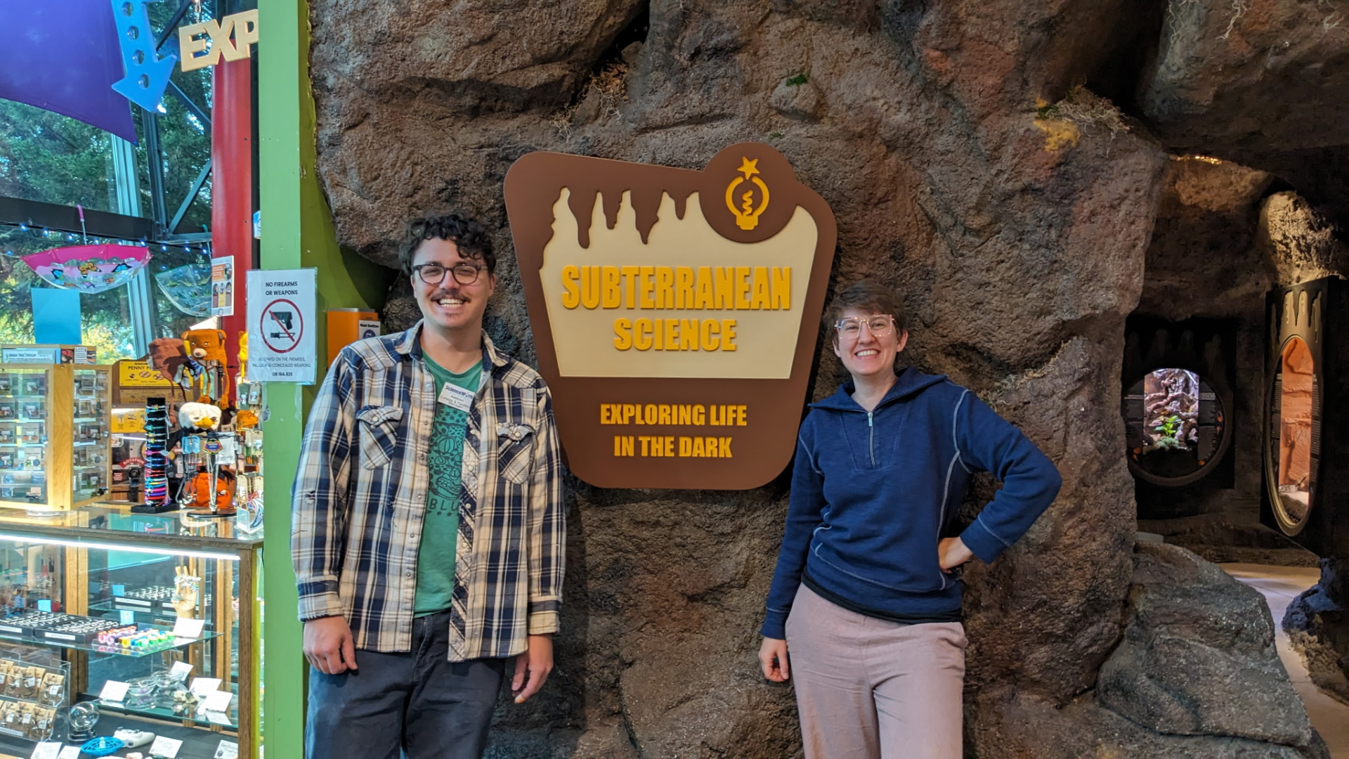 Photo of Addison Carroll and Liz Koonce posed in front of the sign for the new cave exhibit