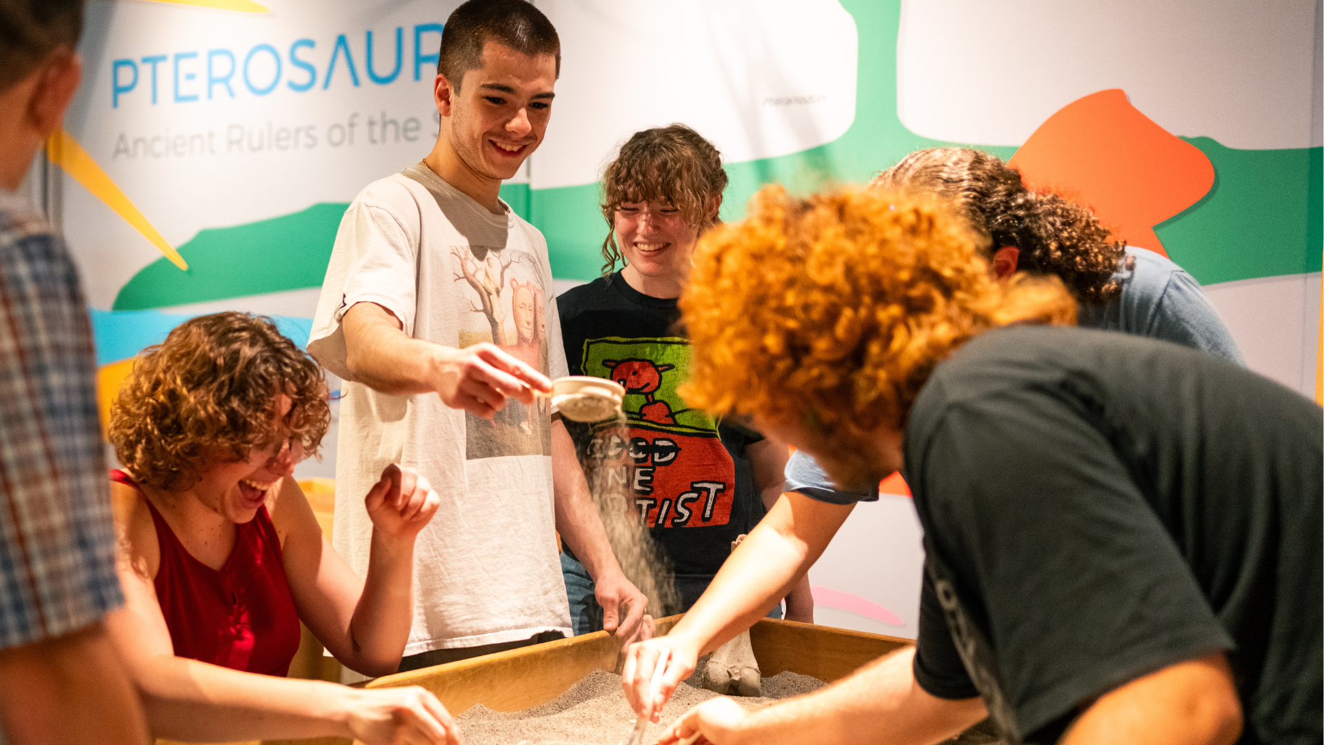 A group of teens exploring the fossil-dig table at ScienceWorks