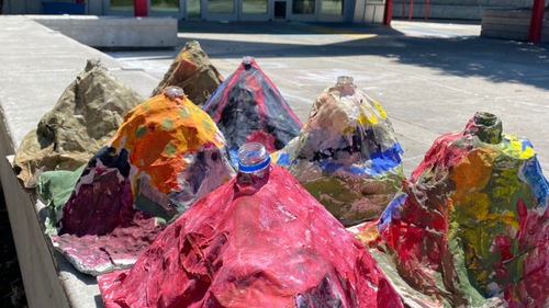 Photo of student-made papier mache volcanos sitting outside in front of ScienceWorks building.