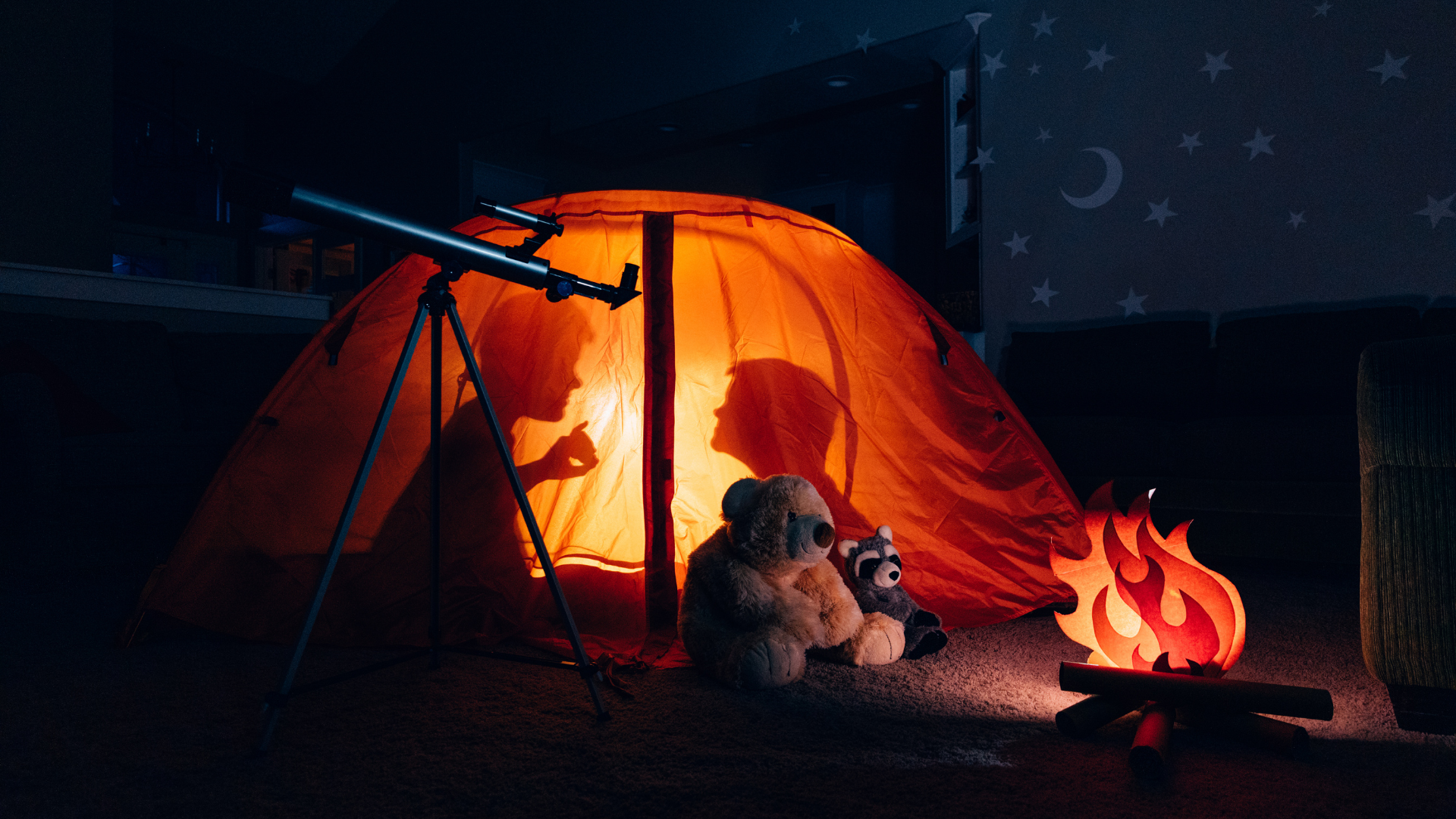 silhouettes of 2 kids inside a camping tent that is lit from within