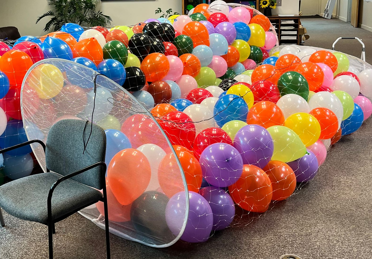 Children gather in a museum space, seated around a map-like structure with orange cones.