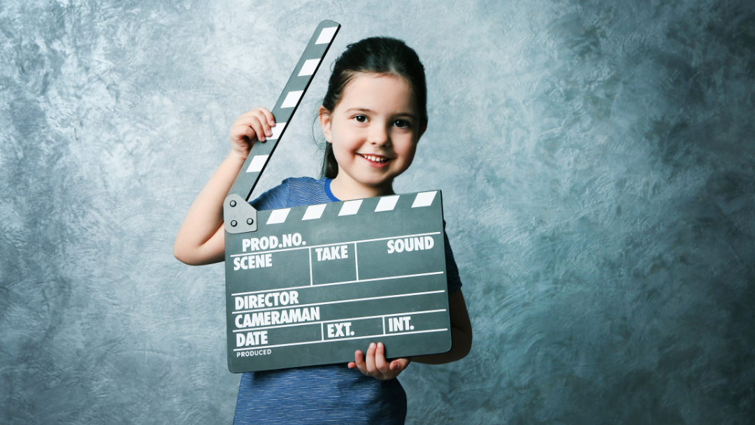 Child holding a director's clapboard.