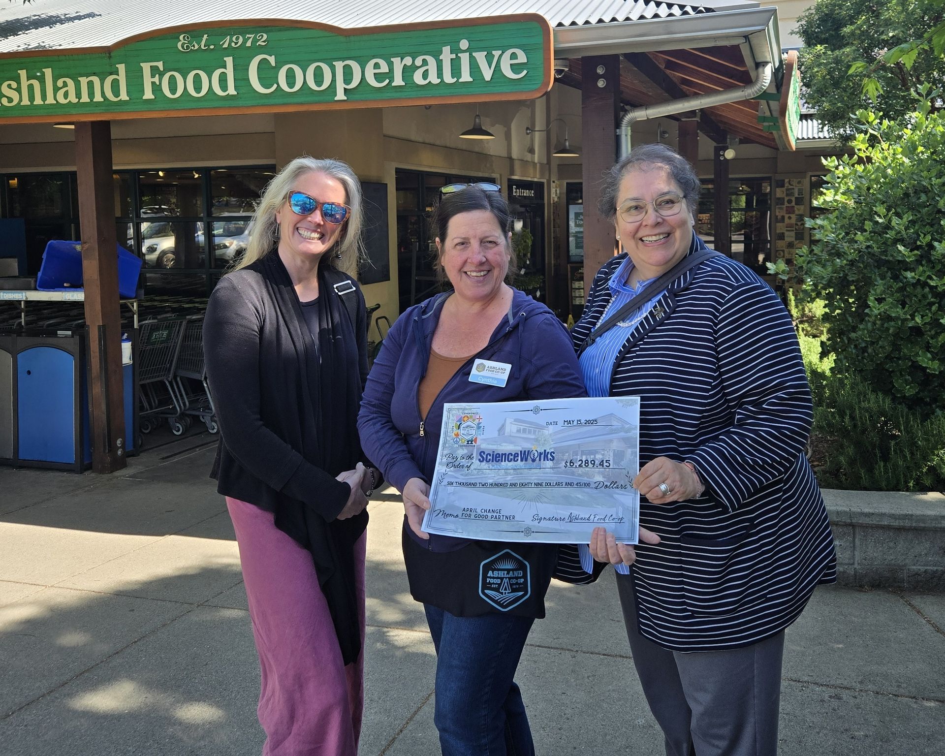 ScienceWorks and Ashland Food Co-op staff pose with a giant sized donation check.