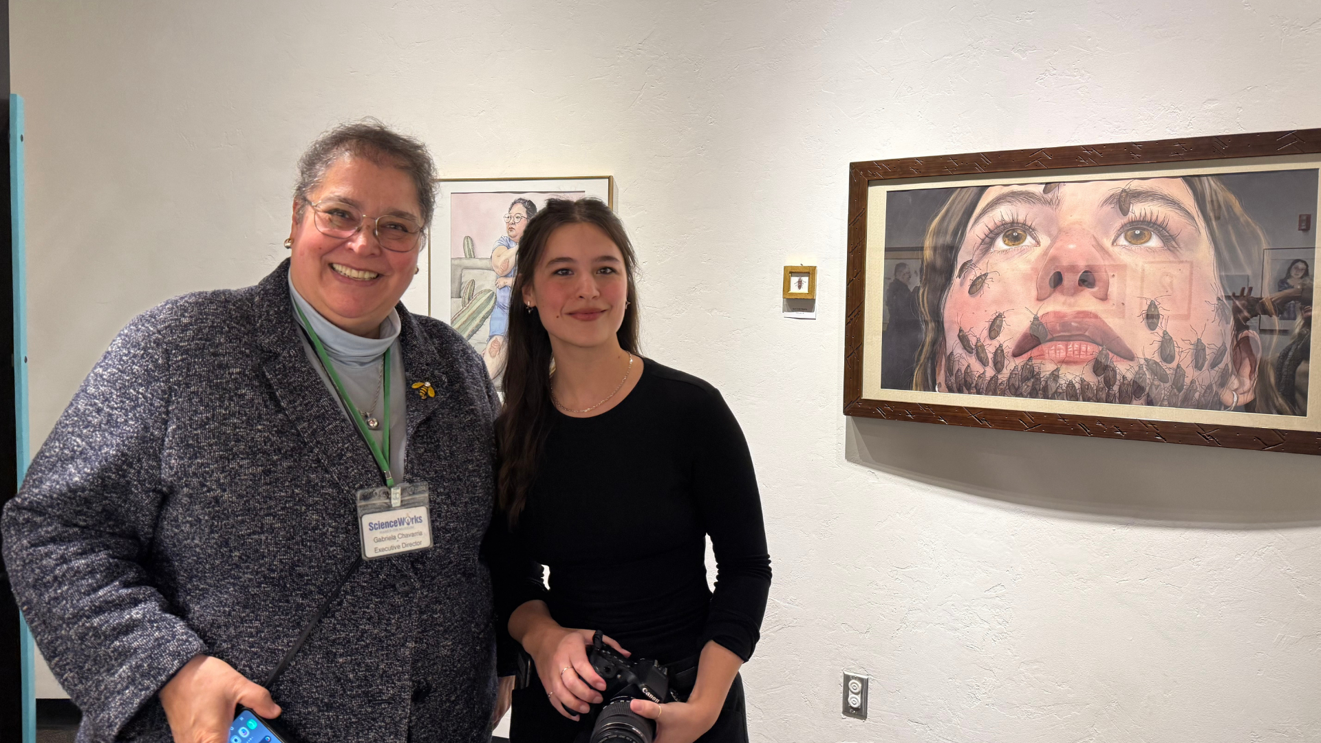 executive director, Gabriela Chavarria, and artist KYRIANNA, pose for a photo at the opening reception of Kyrianna's exhibit, Chronic Conditions Through the lens of nature.