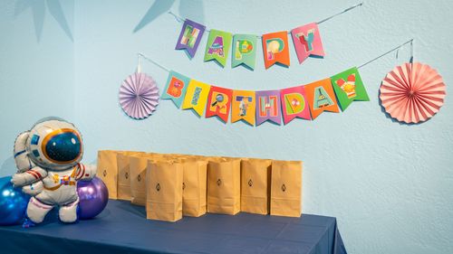 A happy birthday sign, an astronaut balloon, and a collection of goody bags on a table in the Celebration Room at ScienceWorks.