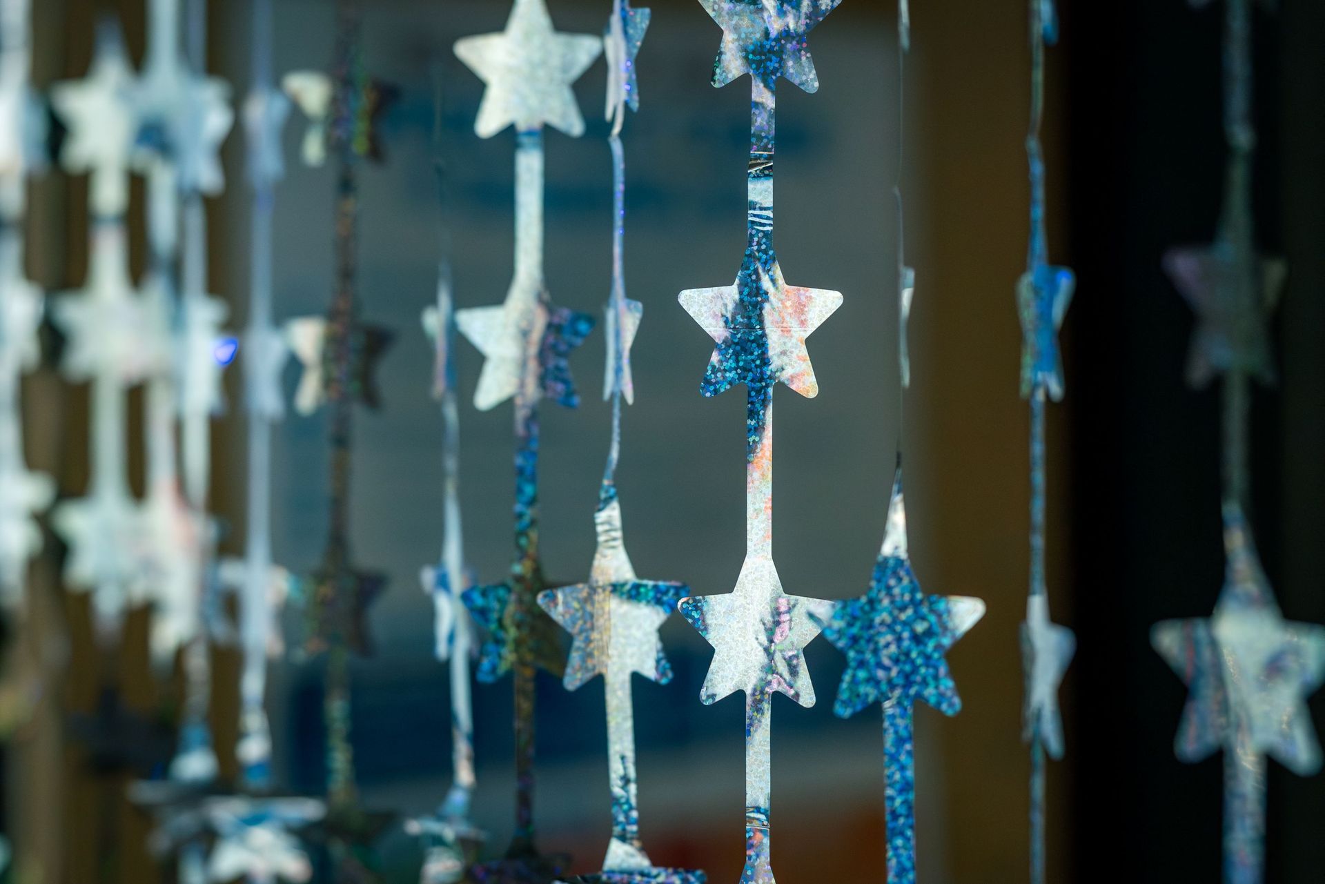 Hanging blue and white star ornaments with glittery ribbons in a row
