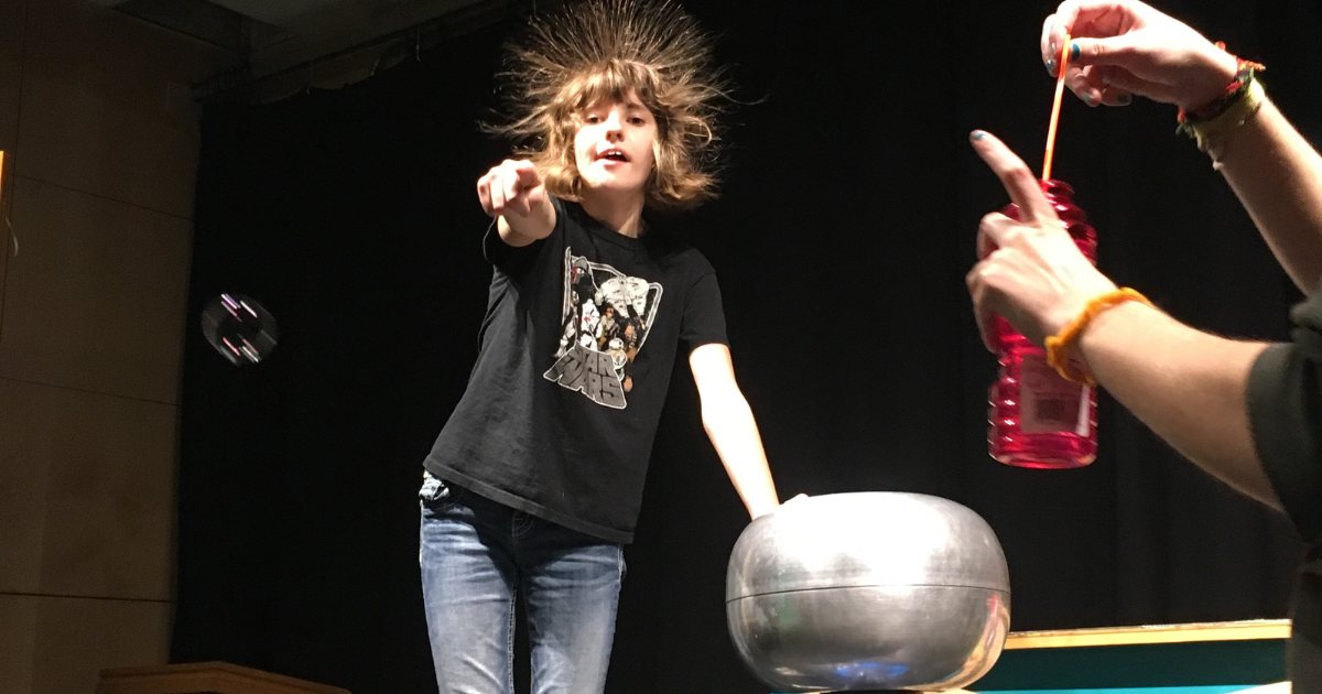 Model of a red muscle Tyrannosaurus Rex in a display case; people looking on.