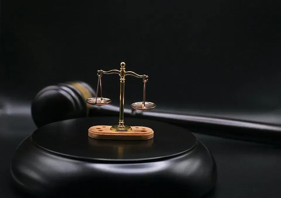 A scale of justice is sitting on top of a wooden block next to a judge 's gavel.