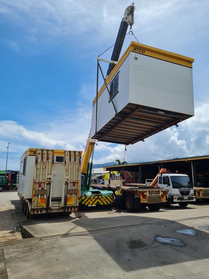A Crane is Lifting a Container From a Truck in a Parking Lot — Bell's Carrying & Crane Hire Service Pty Ltd in Mareeba, QLD