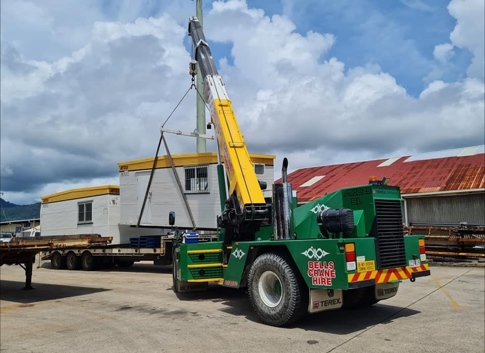 a Green Truck With a Yellow Crane is Parked in a Lot — Bell's Carrying & Crane Hire Service Pty Ltd in Chillagoe, QLD