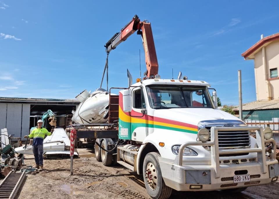 A Man Stands Next to a Truck With a Crane — Bell's Carrying & Crane Hire Service Pty Ltd in Townsville, QLD