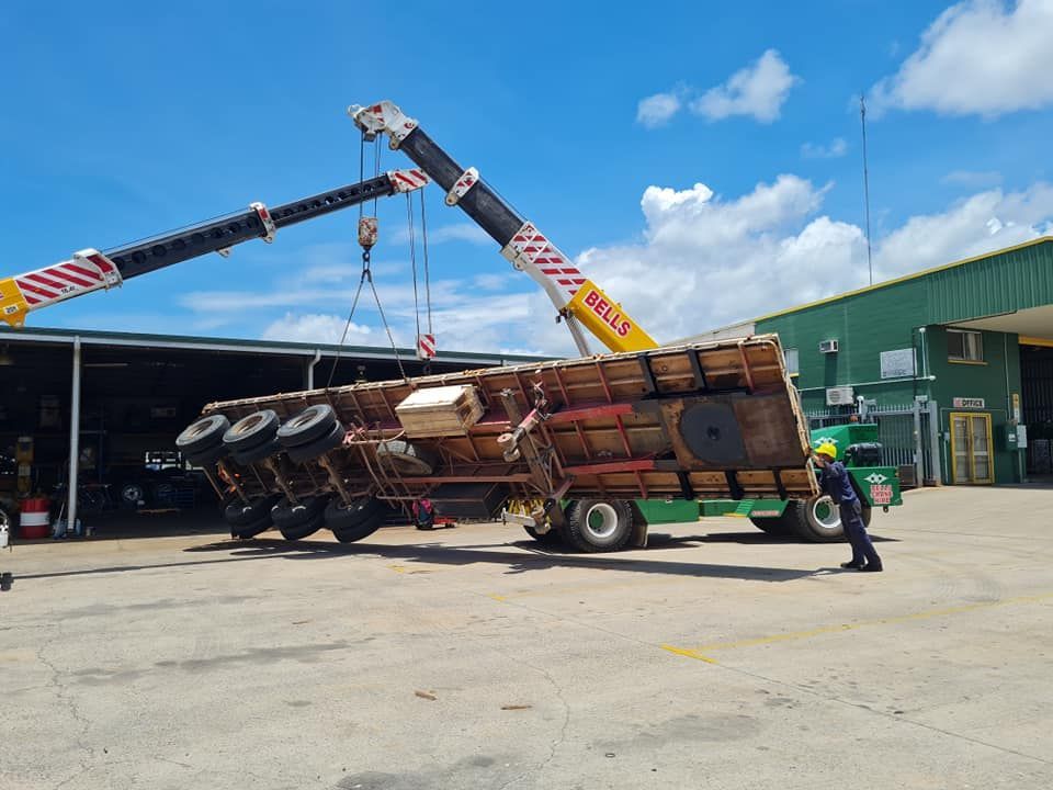 A Truck is Being Lifted by a Crane in a Parking Lot — Bell's Carrying & Crane Hire Service Pty Ltd in Mareeba, QLD