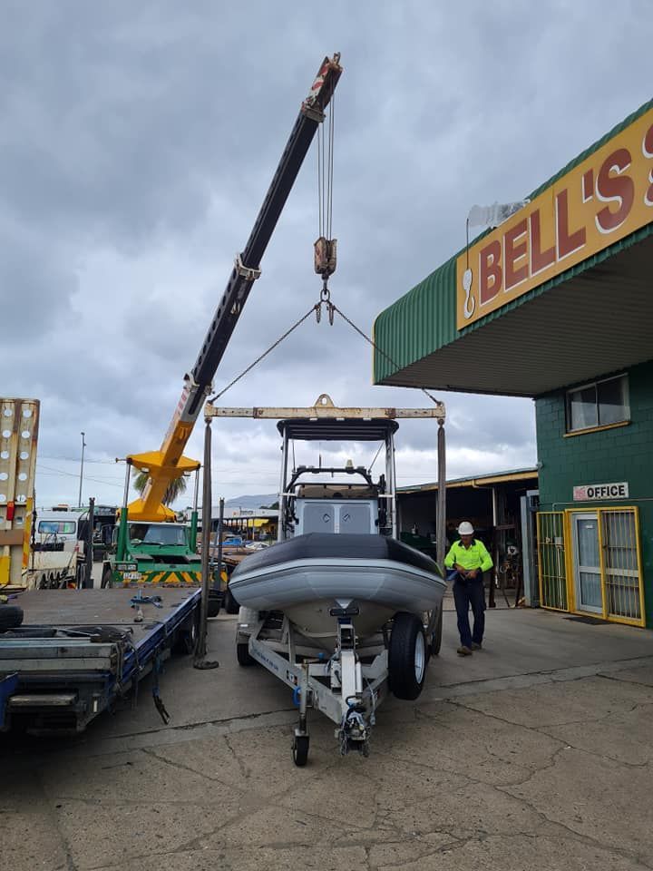 A Boat is Being Lifted by a Crane in Front of Bell 's — Bell's Carrying & Crane Hire Service Pty Ltd in Bungalow, QLD