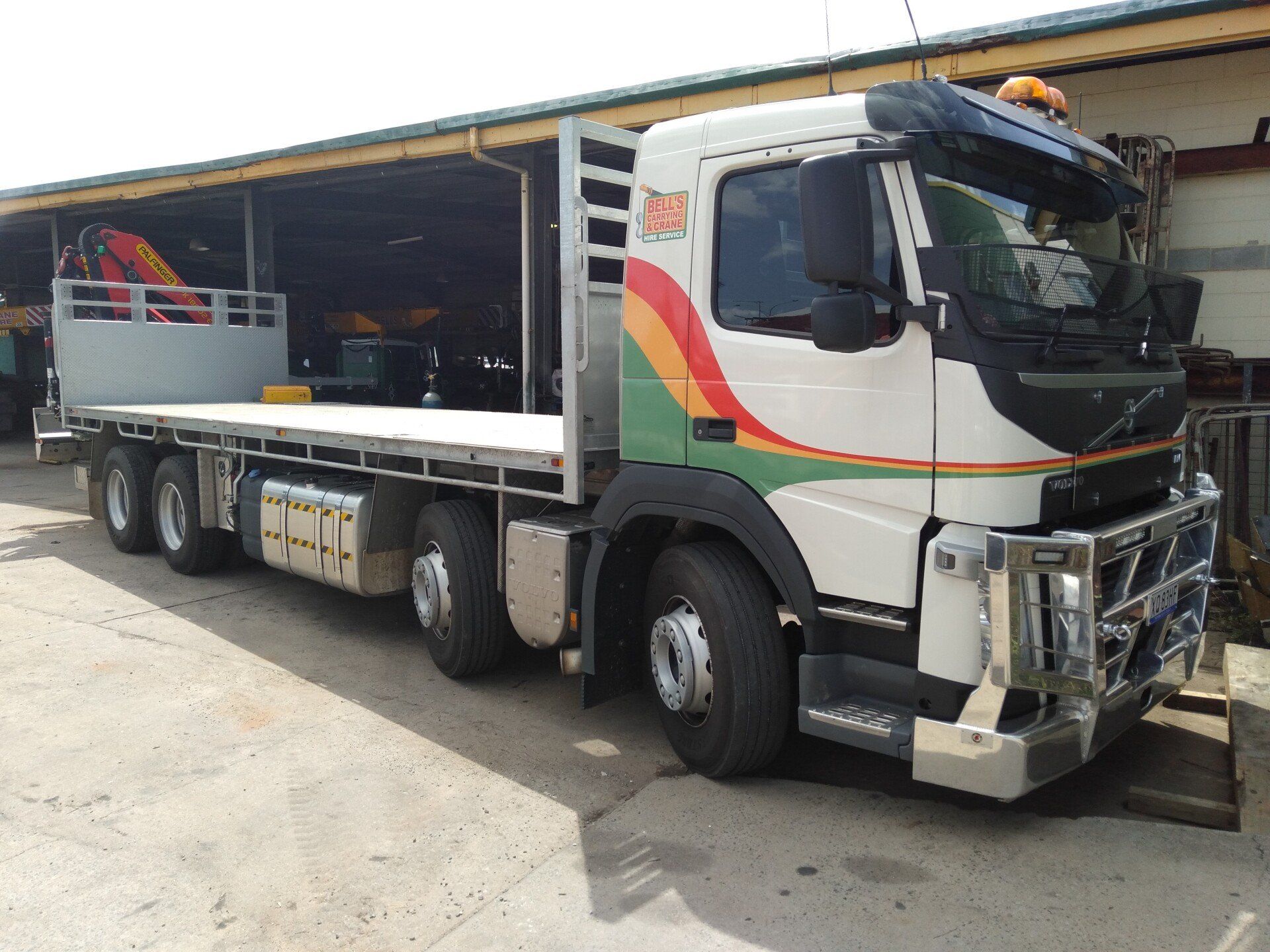 A Flatbed Truck is Parked in Front of a Building — Bell's Carrying & Crane Hire Service Pty Ltd in Bungalow, QLD