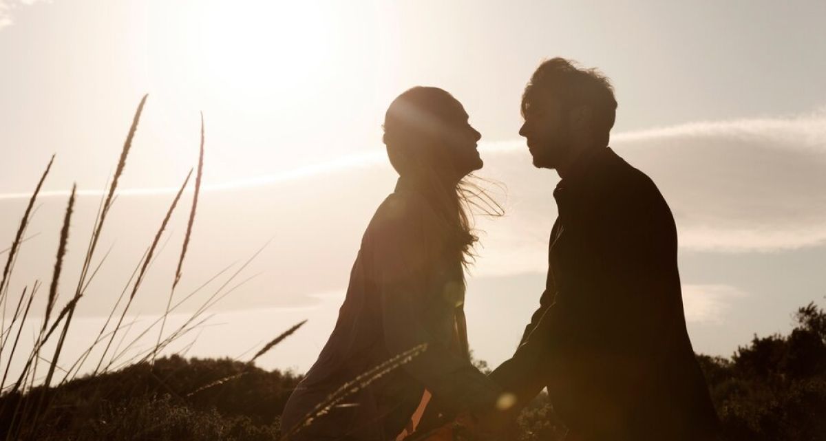 A man and a woman are looking at each other in a field.
