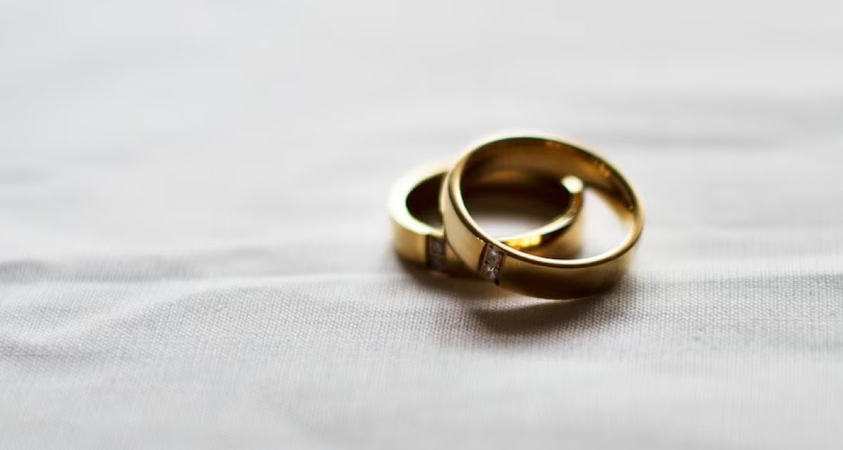Two gold wedding rings are sitting on a white cloth.