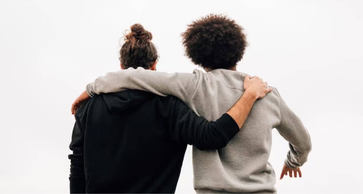 Two men are standing next to each other with their arms around each other 's shoulders.