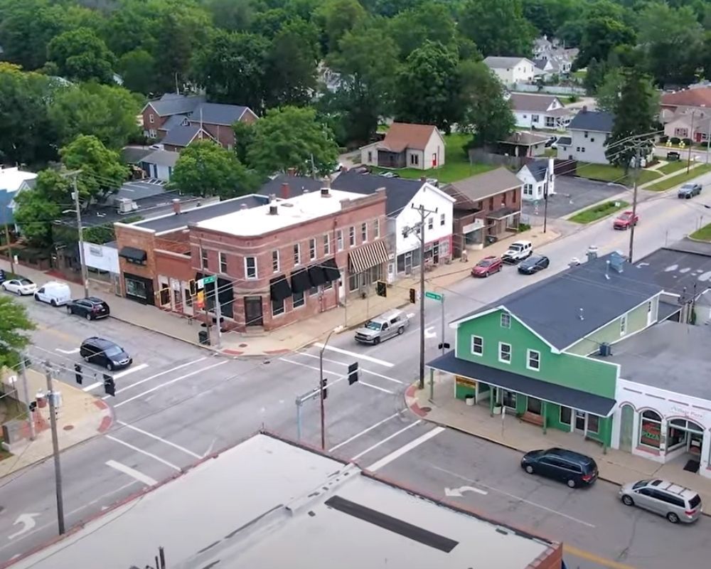 An aerial view of a small town with a green building in the middle of the street.
