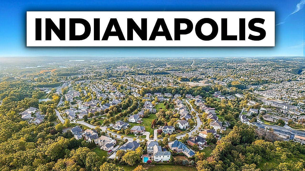 Aerial view of Indianapolis, showcasing a residential area with houses and trees under a blue sky.