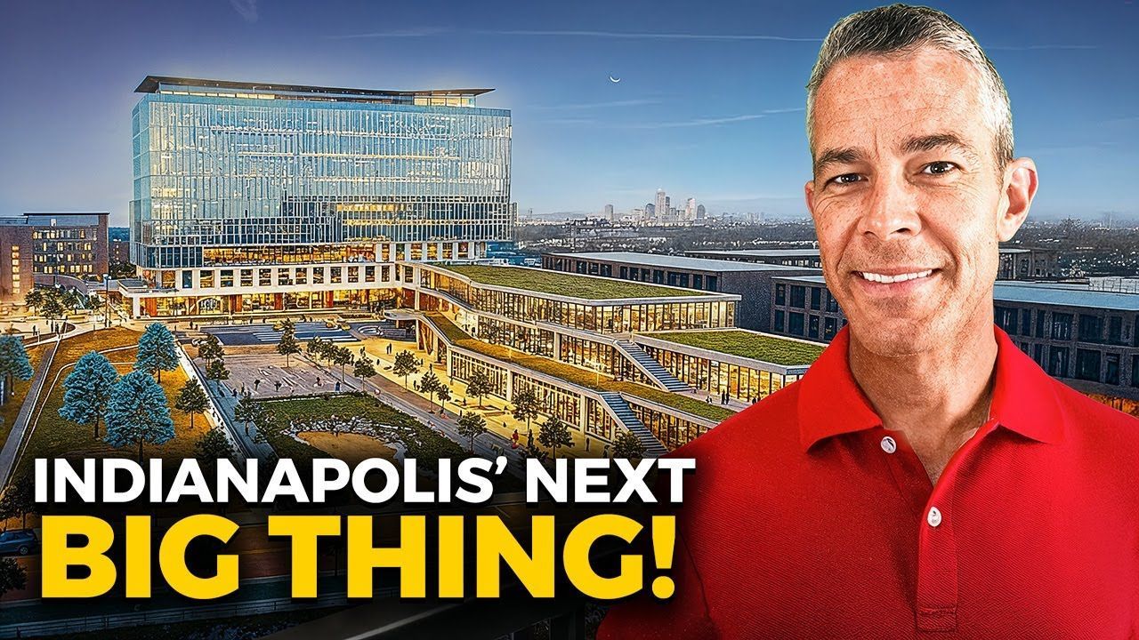 A man in a red shirt is standing in front of a large building.