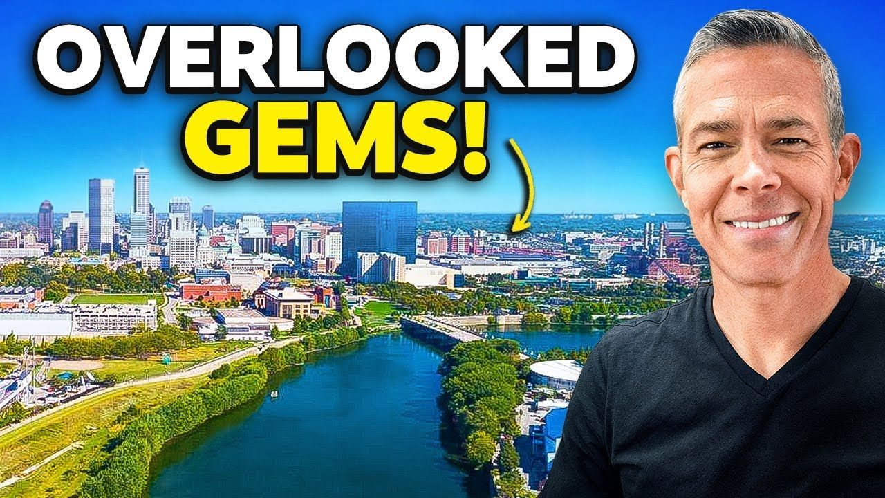 A man is smiling in front of an aerial view of a city and a river.