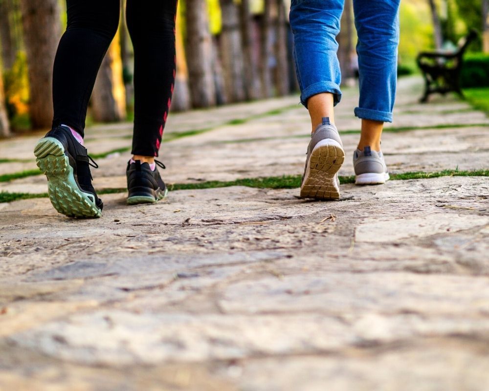 Two people are walking down a stone path in a park.