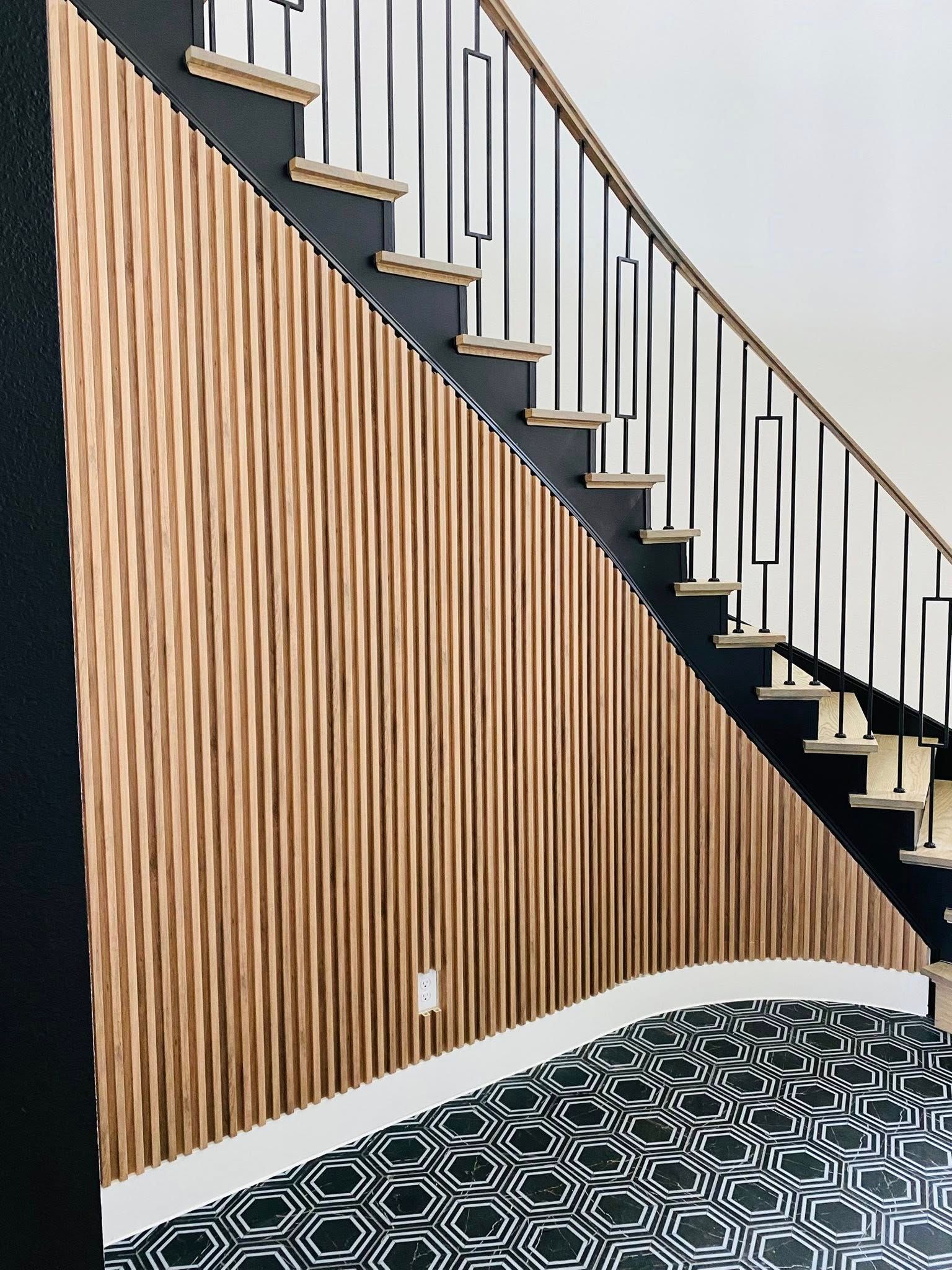 Staircase with wooden panel wall and black and white patterned floor. Black railing and steps.