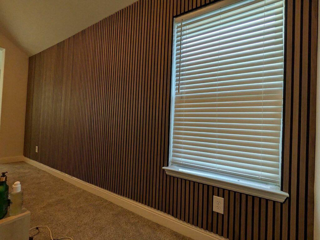 Room with brown vertical striped wall, window with blinds.