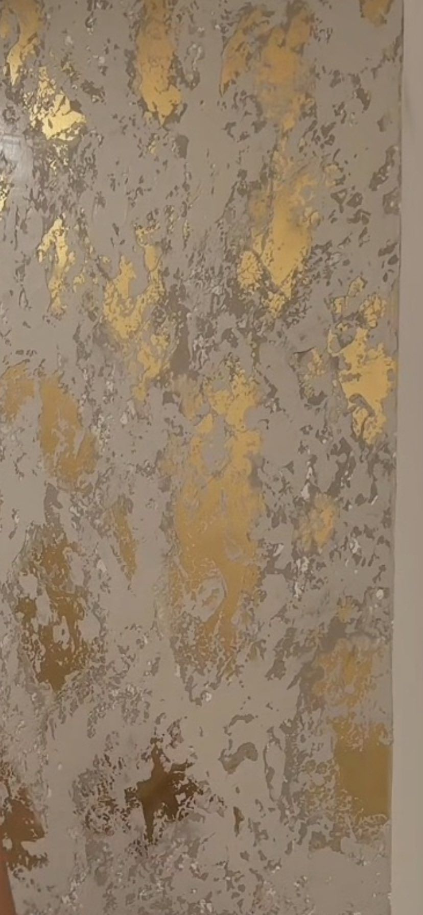 Wall with a textured design featuring gold leaf accents on a grey background.