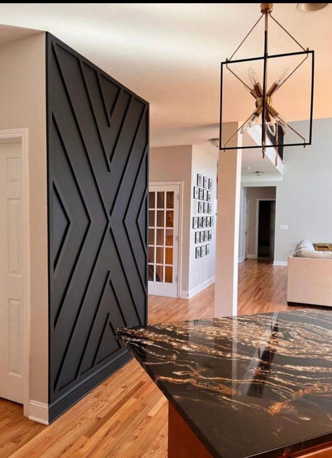 Geometric black accent wall in a modern home, with a black and gold chandelier.