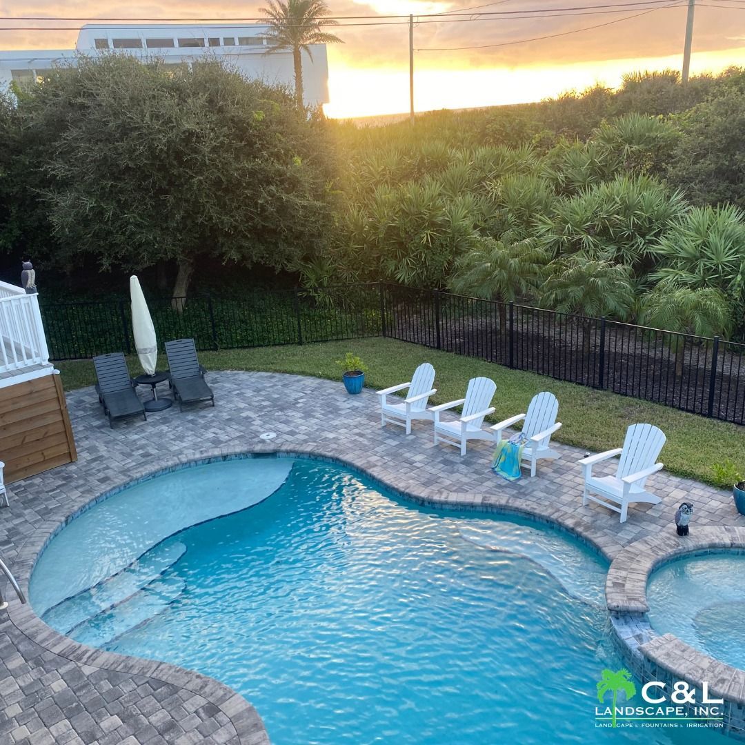 Pool and patio with lounge chairs; view of ocean at sunset.