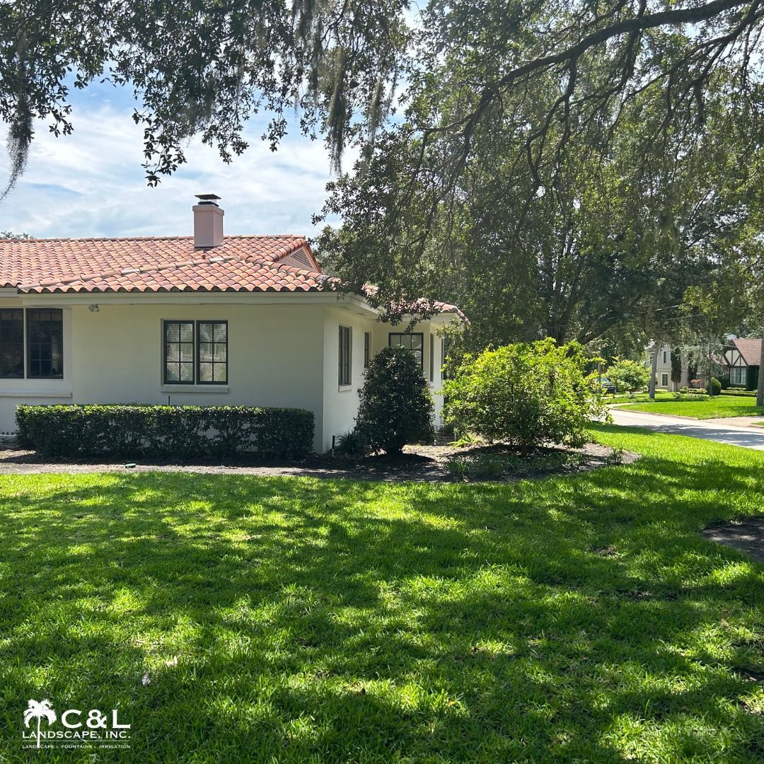 White stucco house with a red tile roof and lush green lawn.