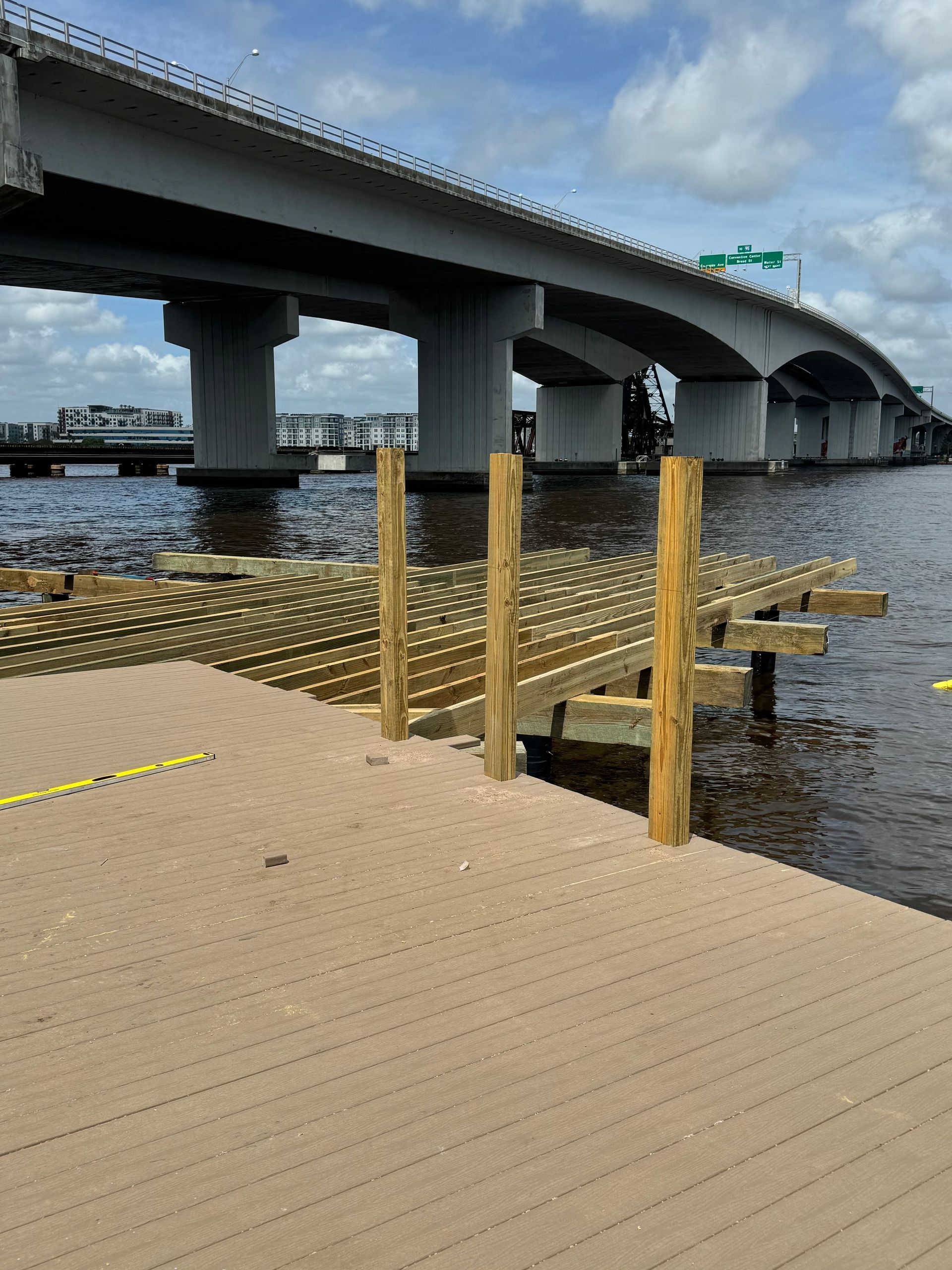 Wooden dock with bridge in background over water, clear sky.