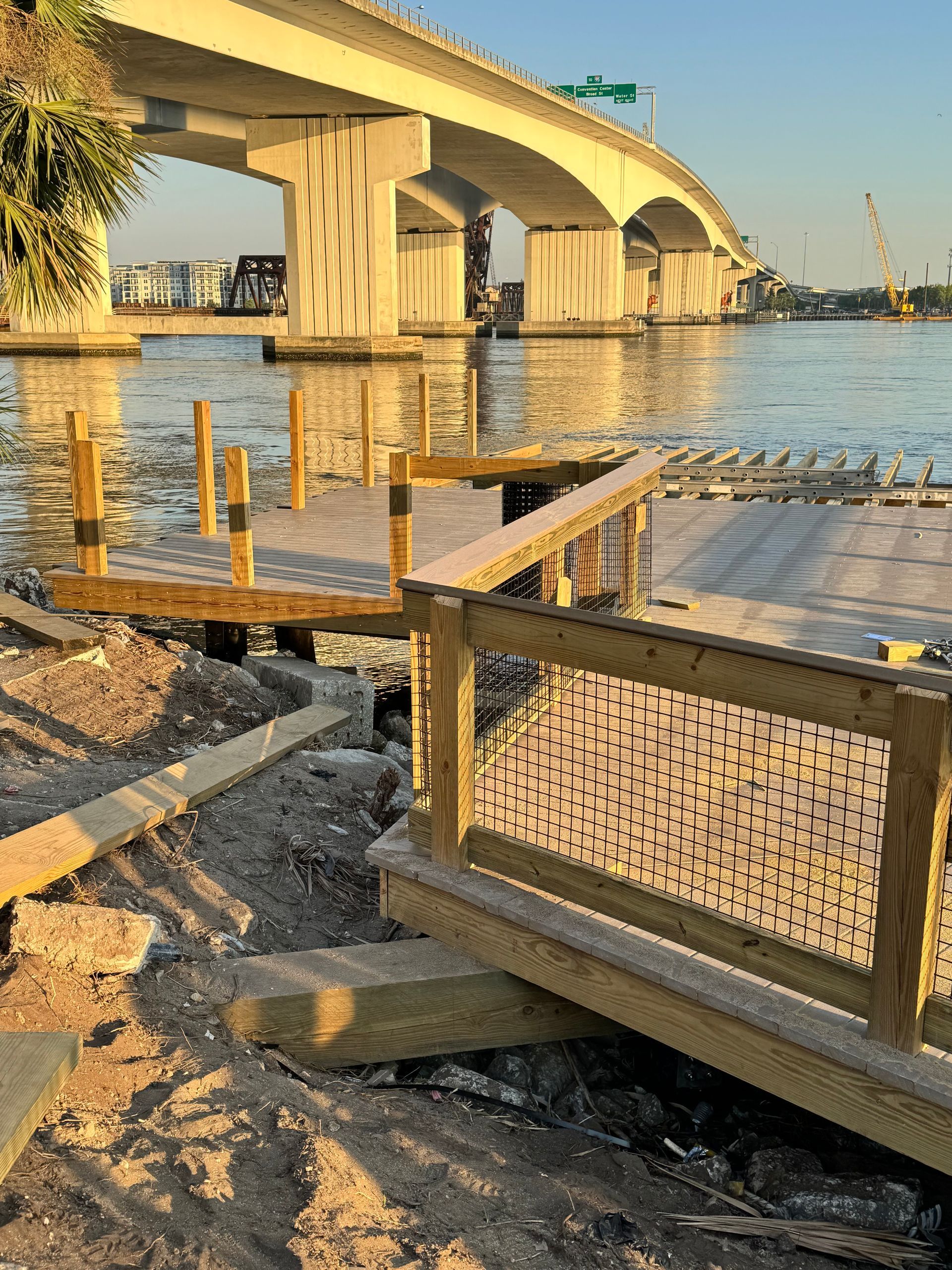 Wooden dock and railing with bridge in background.