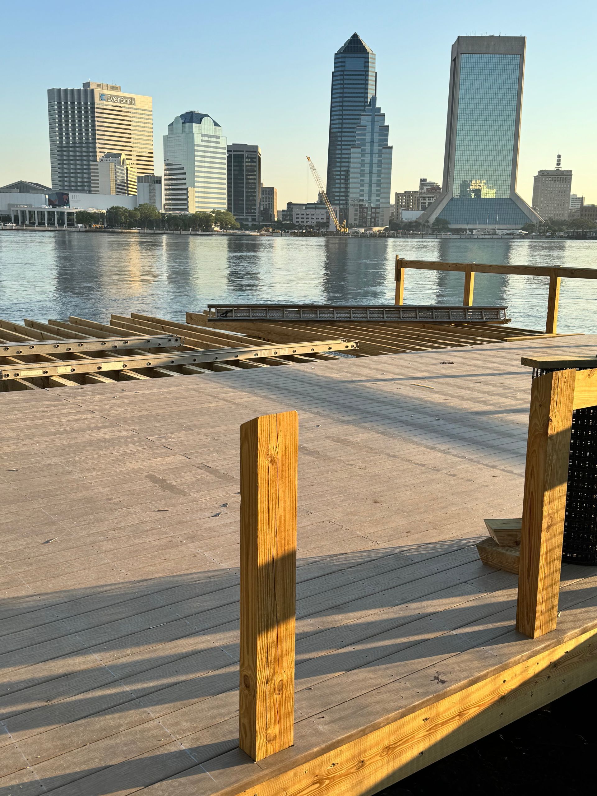 Wooden pier with city skyline in the background, water in between.