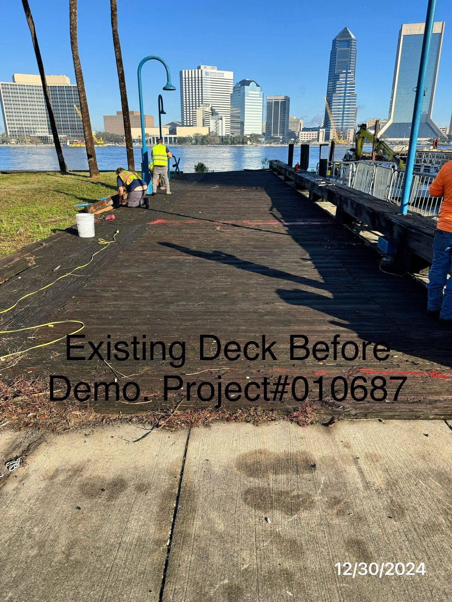 Wooden dock before demolition with city skyline in the background; sunny day.