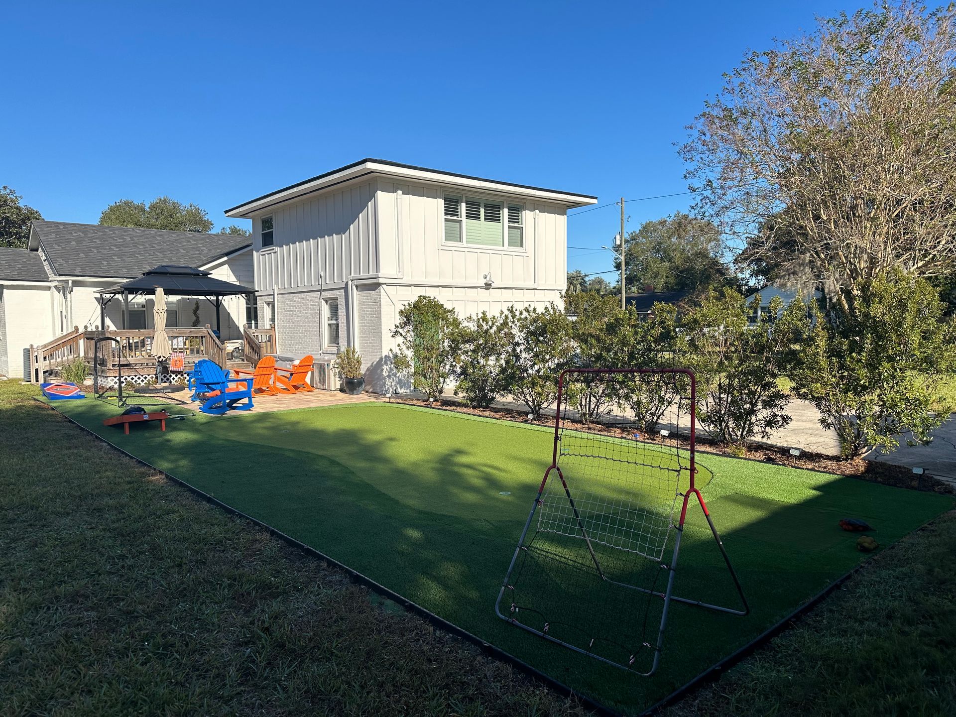 Backyard with green turf and a swing set, house in background.