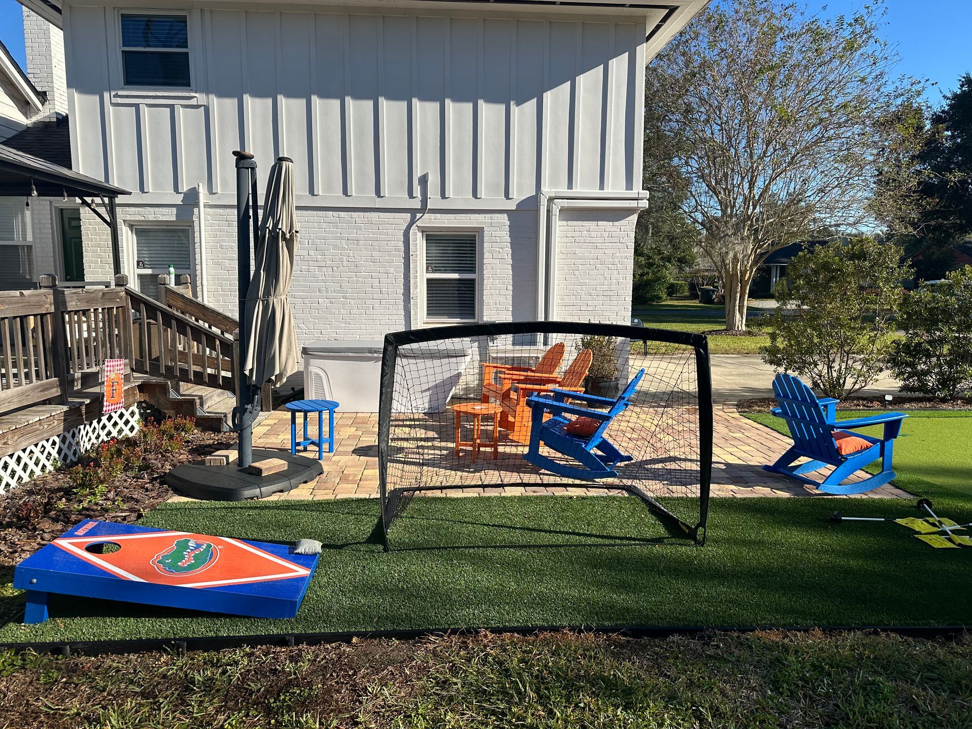 Backyard scene with lawn, patio furniture, and cornhole game.