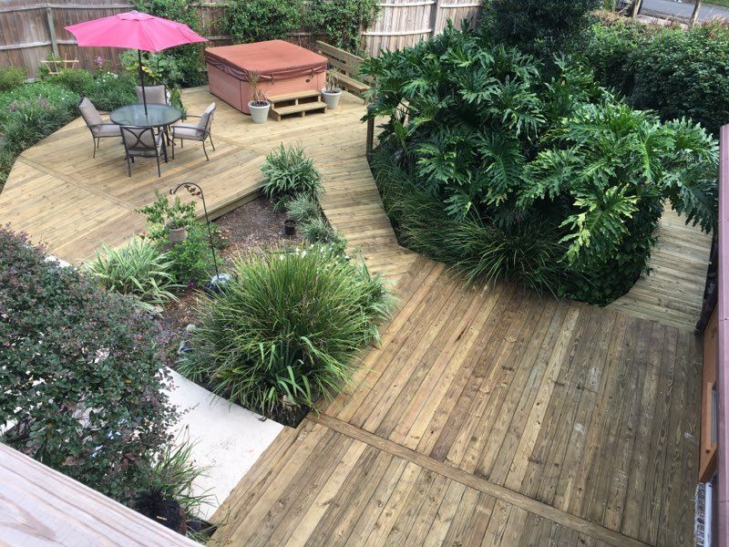 Wooden deck with a hot tub, table, chairs, and garden.