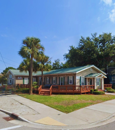 Pool with white Adirondack chairs, a hot tub, and a black fence in the backyard.