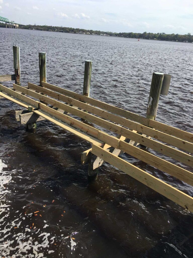 Partially constructed wooden pier extending into dark water.