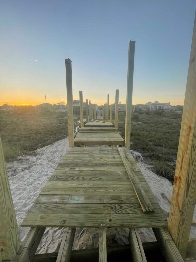 Wooden pier under construction, stretching towards the horizon. Wooden posts stand upright along the deck.