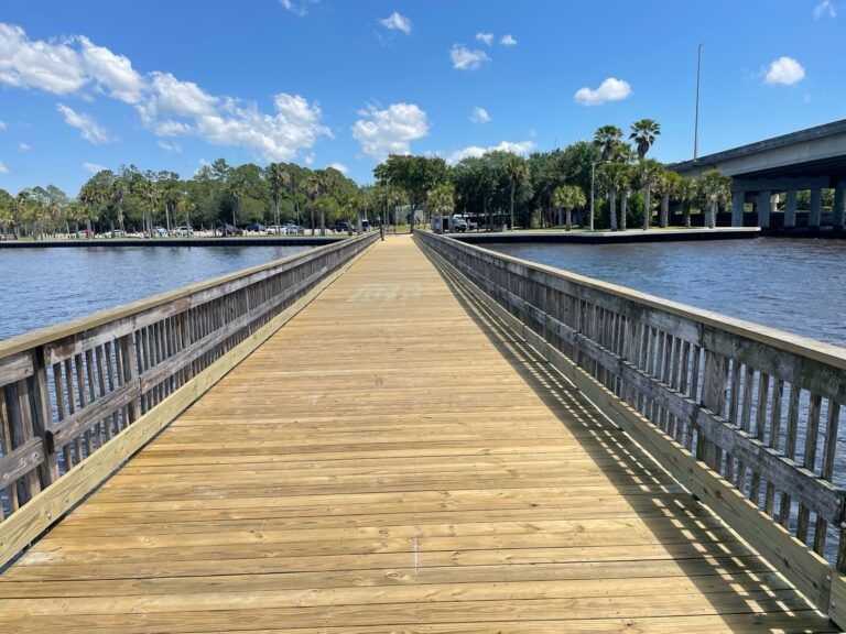 Wooden pier extending over water, under a blue sky.